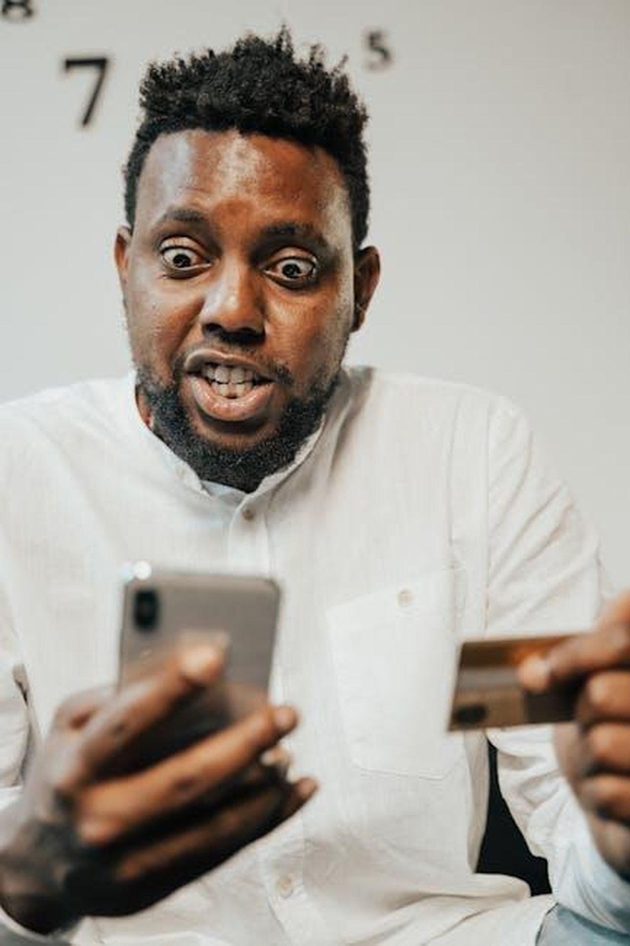 La_reazione_di_Shaila_fTDViAYg5w - Confidenze24 Source: Tima Miroshnichenko - pexels - A surprised man holding a credit card and smartphone, engaged in online shopping.