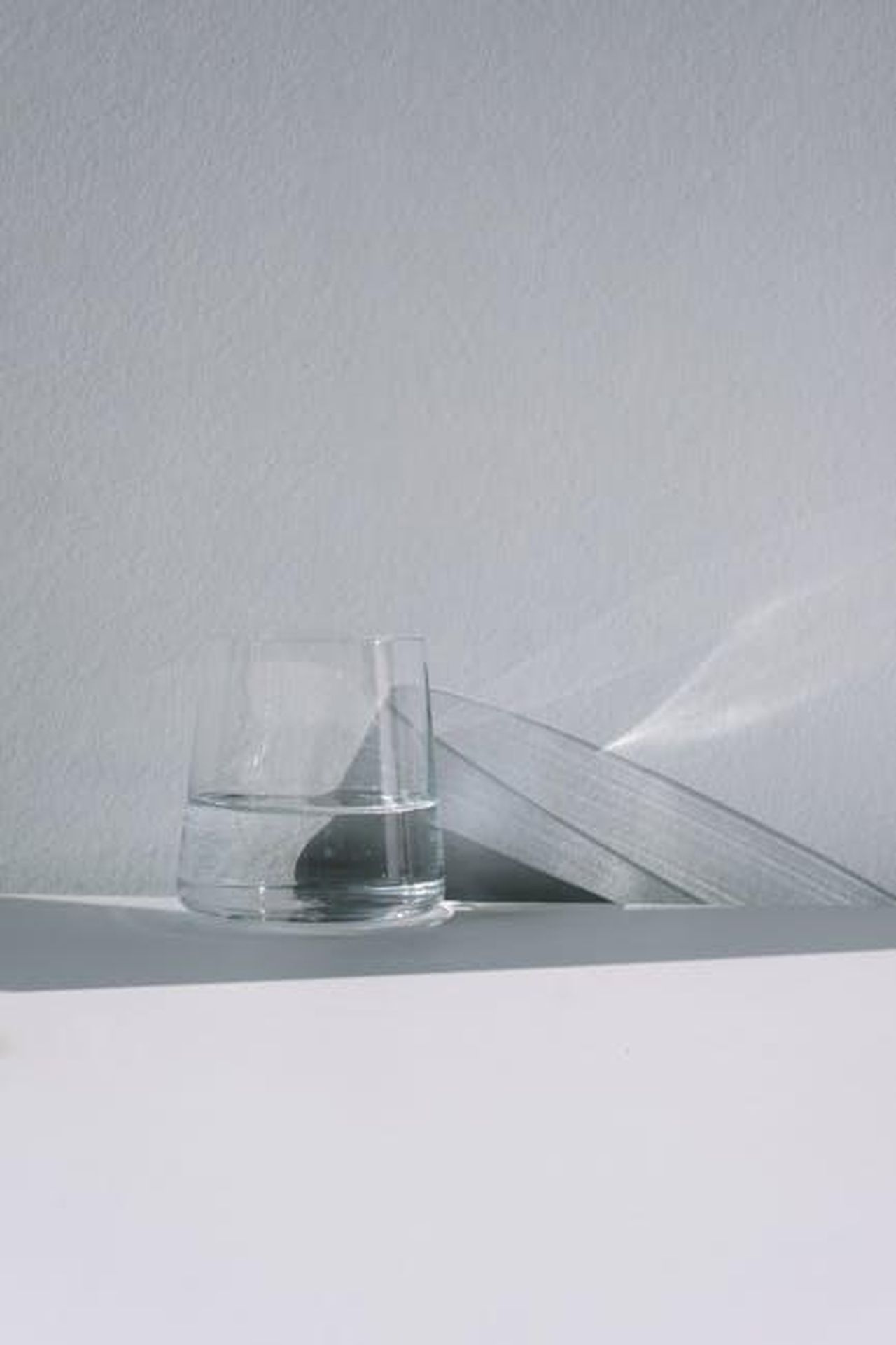 La_sobriet_di_Affleck_come_priorit_Atdnhhy1Rv - Confidenze24 Source: cottonbro studio - pexels - Elegant minimalist setup with a clear glass of water and an open book on a white table.
