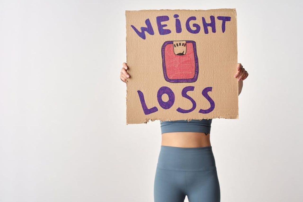 La_straordinaria_perdita_di_peso_di_Mark_Labbett_eQ4nhW70nq - Confidenze24 Source: Moe Magners - pexels - Person holding 'weight loss' sign for fitness motivation and health goals.