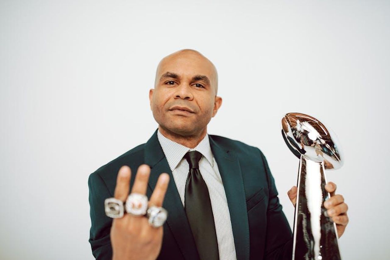 La_sua_esperienza_con_la_fama_wnLNPsCETB - Confidenze24 Source: RDNE Stock project - pexels - Confident man in a suit showcasing victory rings and trophy on a white background.