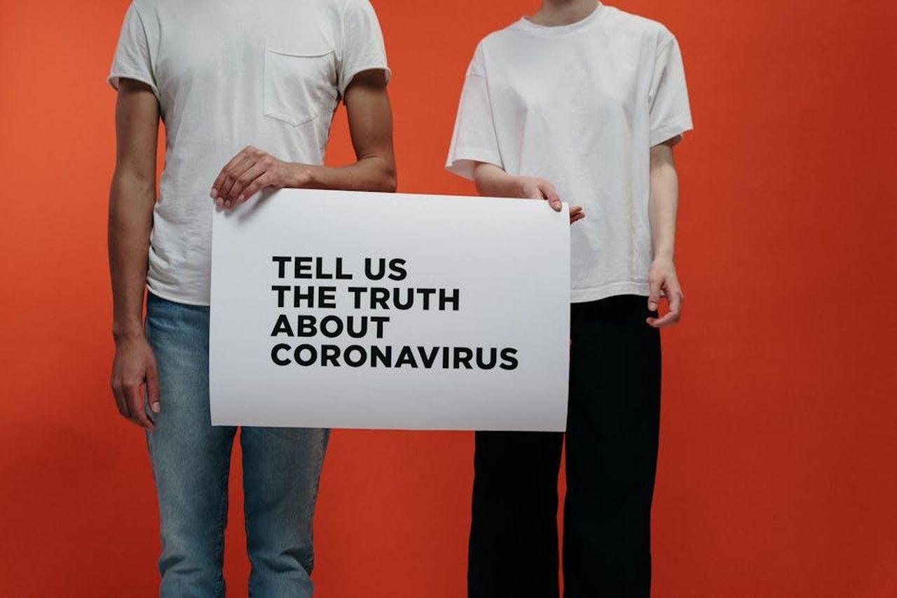 La_verit_nascosta_tzB1Zl4BtB - Confidenze24 Source: cottonbro studio - pexels - Two individuals holding sign demanding truth about coronavirus against orange background.