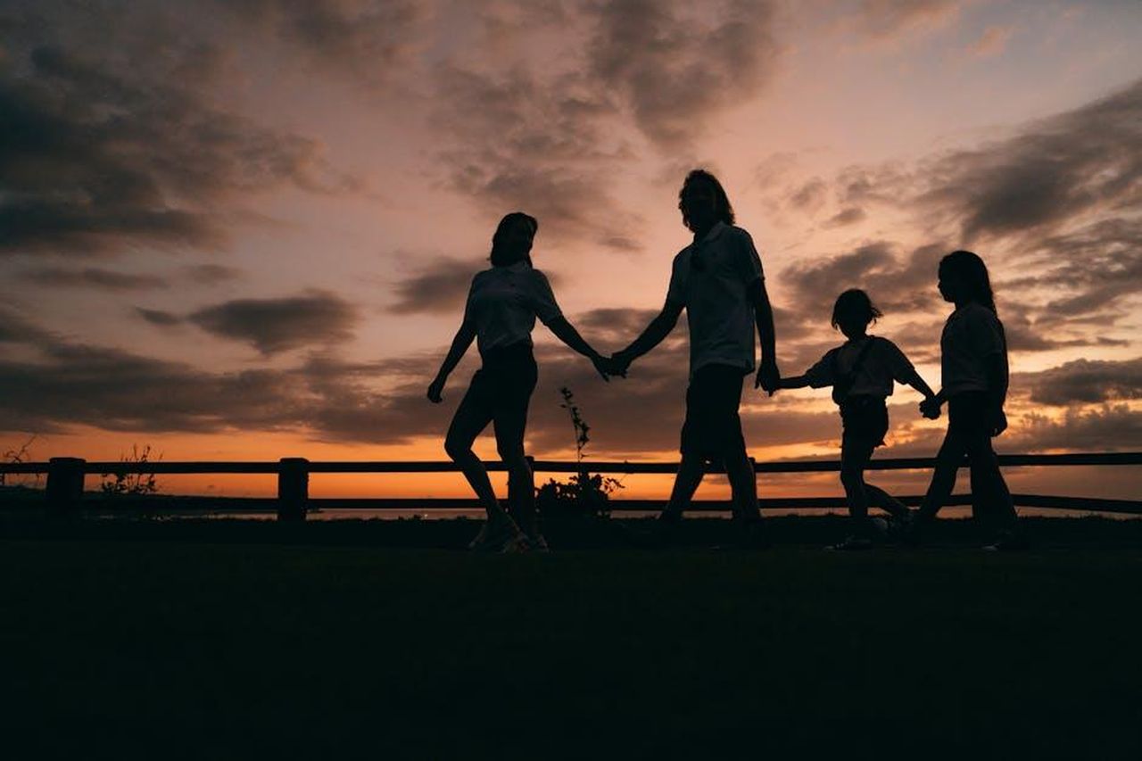 La_vita_sociale_a_Mustique_tUpqJsxZrK - Confidenze24 Source: Mikhail Nilov - pexels - A family walks hand in hand against a vibrant sunset, evoking togetherness and peace.