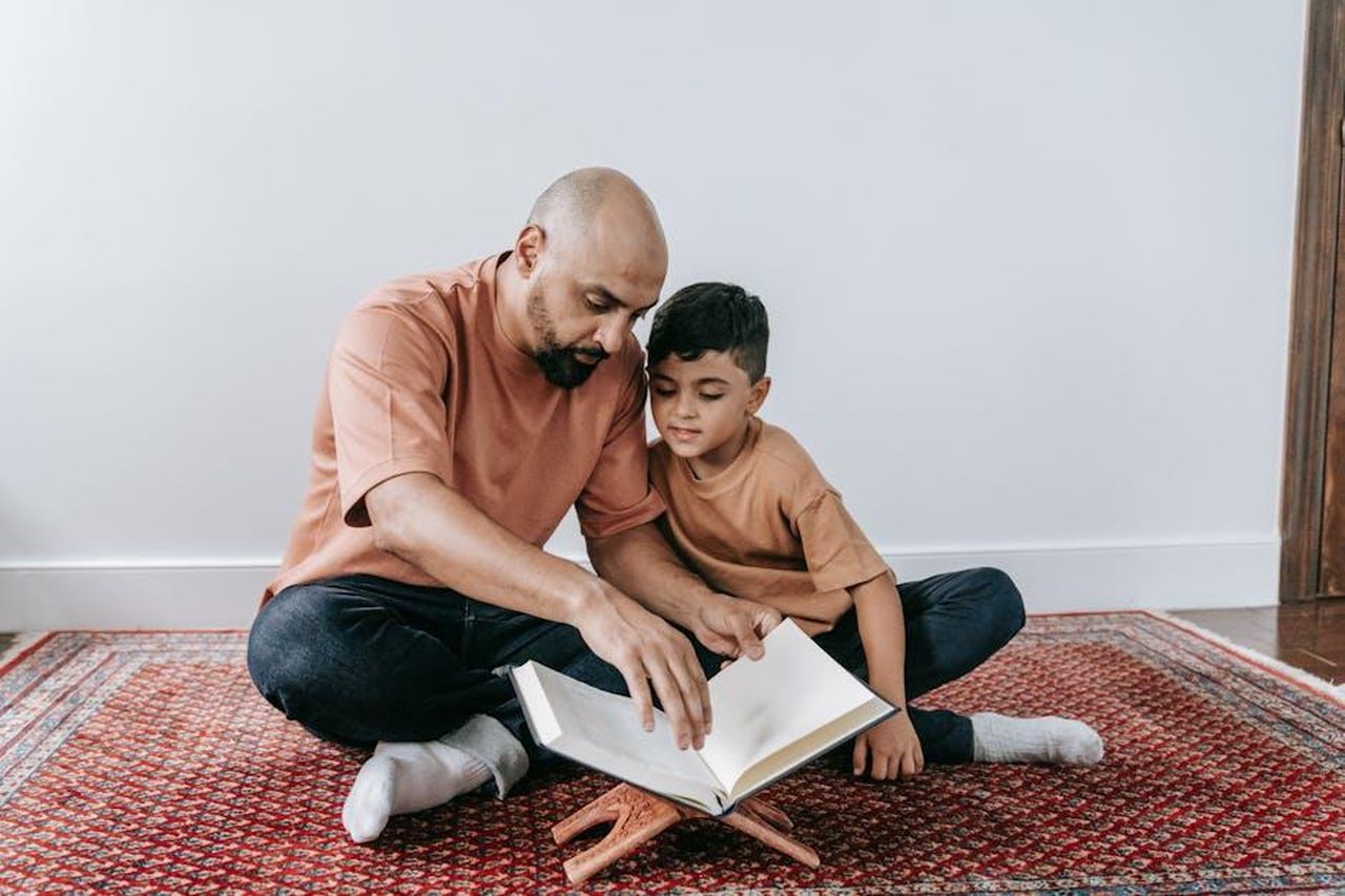 Lamara_sorpresa_per_Yesim_leggendo_il_testamento_di_Tarik_Ukxd3y1rcw - Confidenze24 Source: Timur Weber - pexels - A father and son sitting on a rug, bonding over reading indoors.