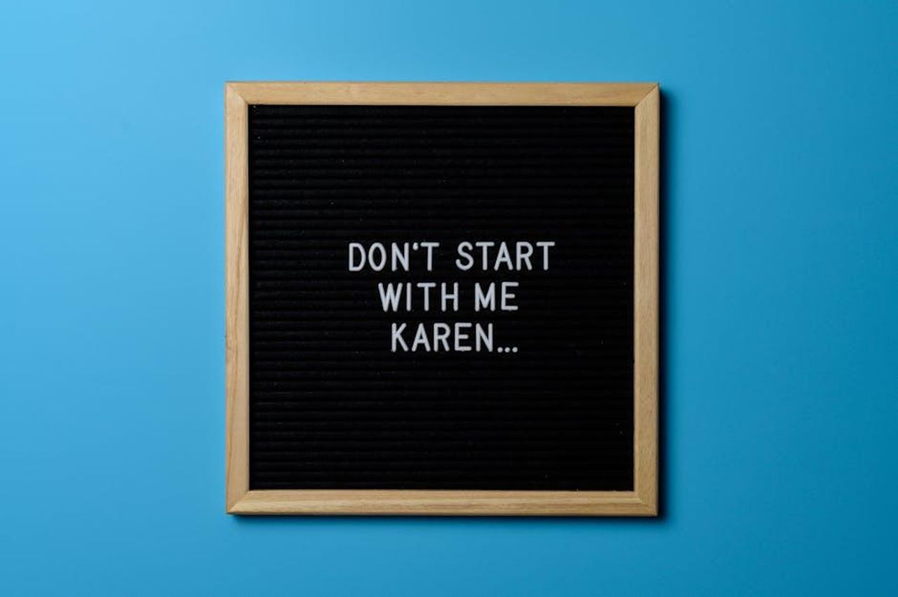 Le_Reazioni_e_le_Dichiarazioni_di_Karen_qCQQAtqKQJ - Confidenze24 Source: Brett Sayles - pexels - Funny text on a black letter board with wooden frame against a blue background, highlighting humor and casual tone.