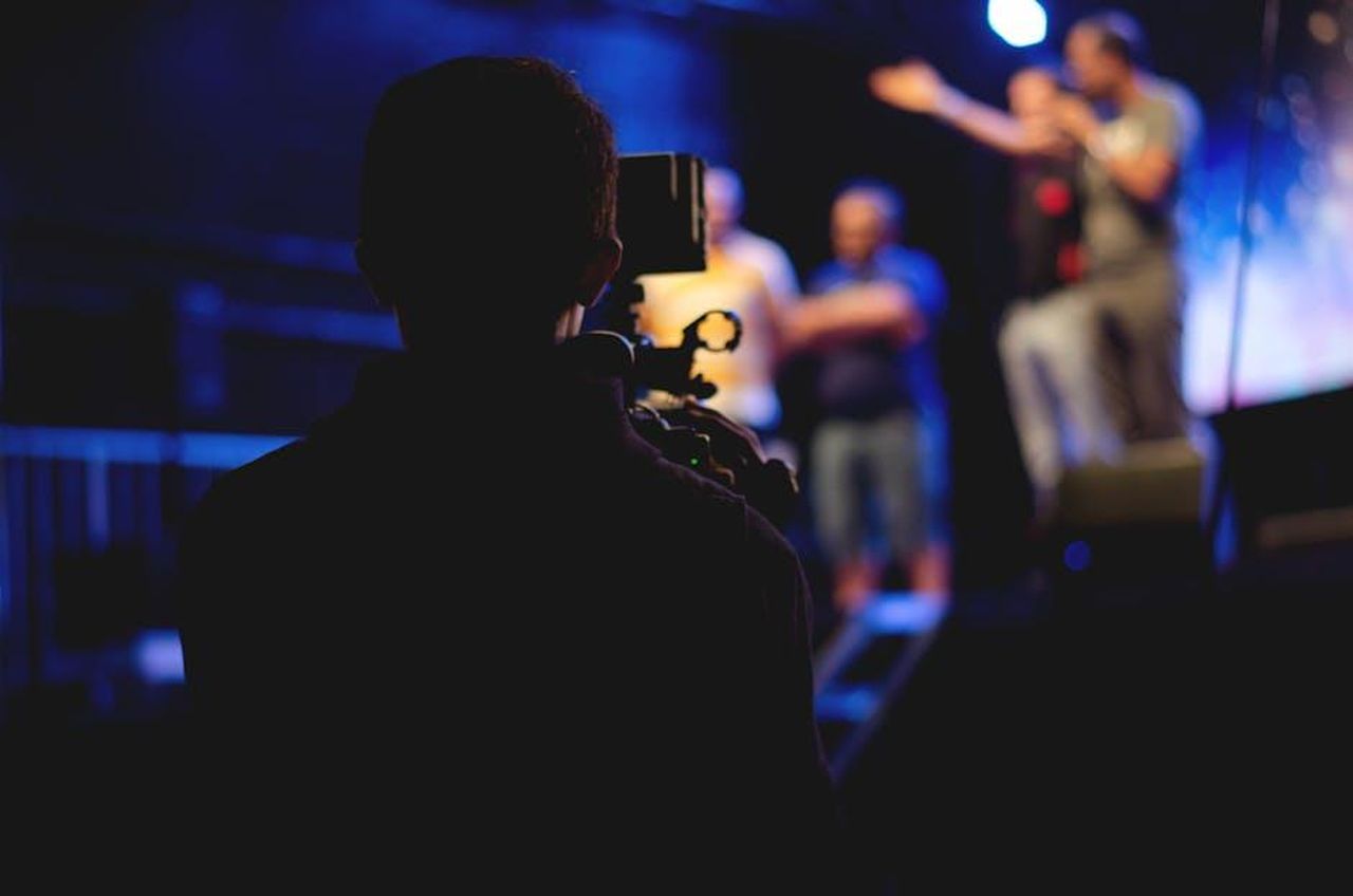 Le_accuse_di_Zeudi_e_le_prove_video_lrzaS1IRDK - Confidenze24 Source: Nino Souza - pexels - A cameraman films a live concert performance, capturing the dynamic stage action.