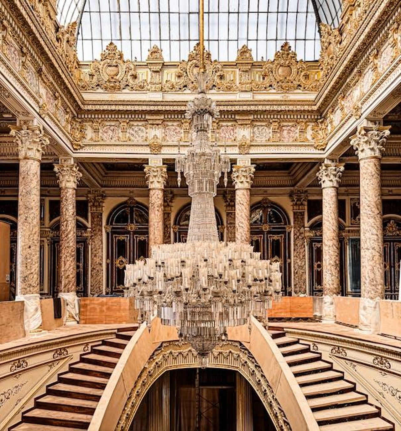Le_dichiarazioni_di_un_commentatore_reale_x6q3TOUEsm - Confidenze24 Source: DUYGU ÇINAR - pexels - Luxurious interior with grand staircase and ornate chandelier under a glass ceiling.