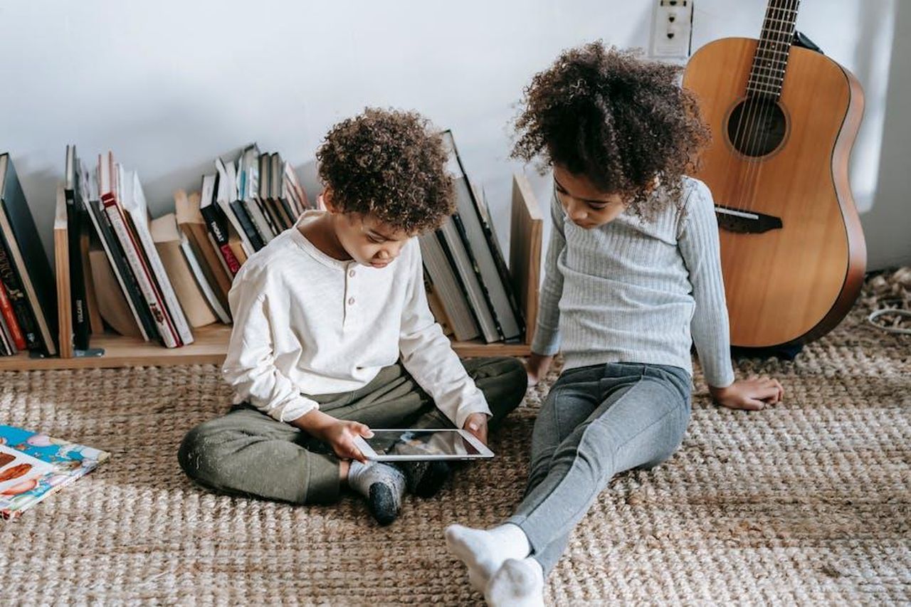 Le_parole_di_Cristiano_Malgioglio_contro_Mogol_YMb1RWKY1x - Confidenze24 Source: Marta Wave - pexels - Thoughtful African American children in casual clothes sitting on floor against guitar and books and using tablet at home in daytime