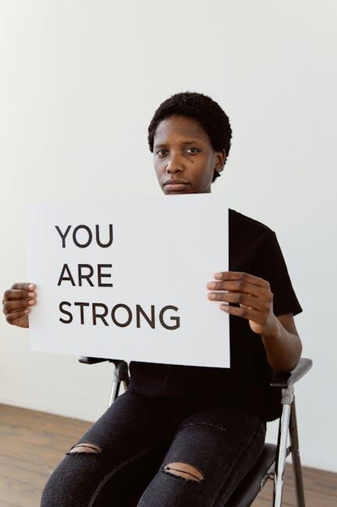Le_parole_di_don_Giuliano_Ha_saputo_sostenere_gli_altri_nonostante_il_dolore_QkAkn0PQRi - Confidenze24 Source: Darina Belonogova - pexels - A portrait of a woman in a wheelchair holding a sign that reads 'YOU ARE STRONG,' promoting empowerment and resilience.
