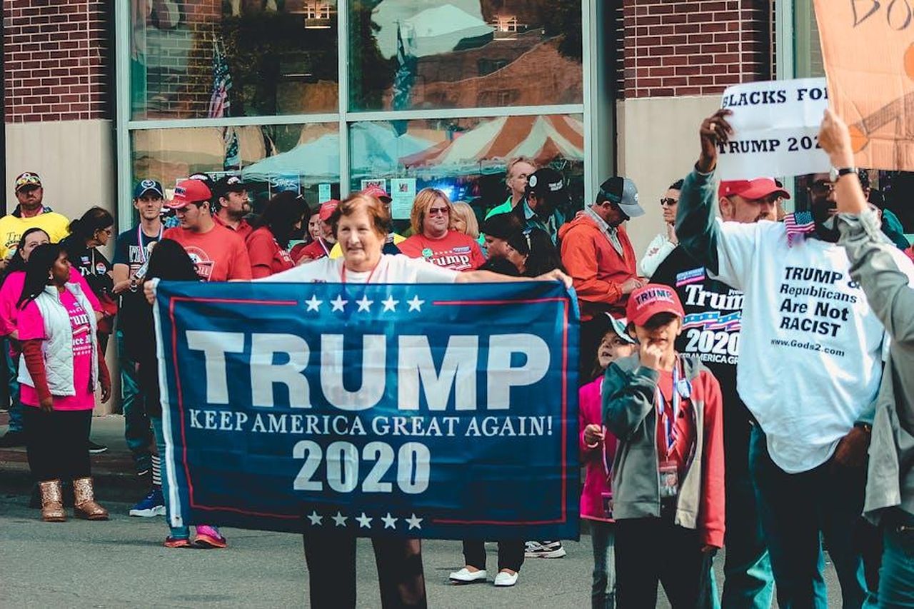 Le_reazioni_alla_decisione_del_NPS_5GYCt3WPTC - Confidenze24 Source: Rosemary Ketchum - pexels - A crowded political rally in Wheeling, showcasing Trump supporters with banners and signs.