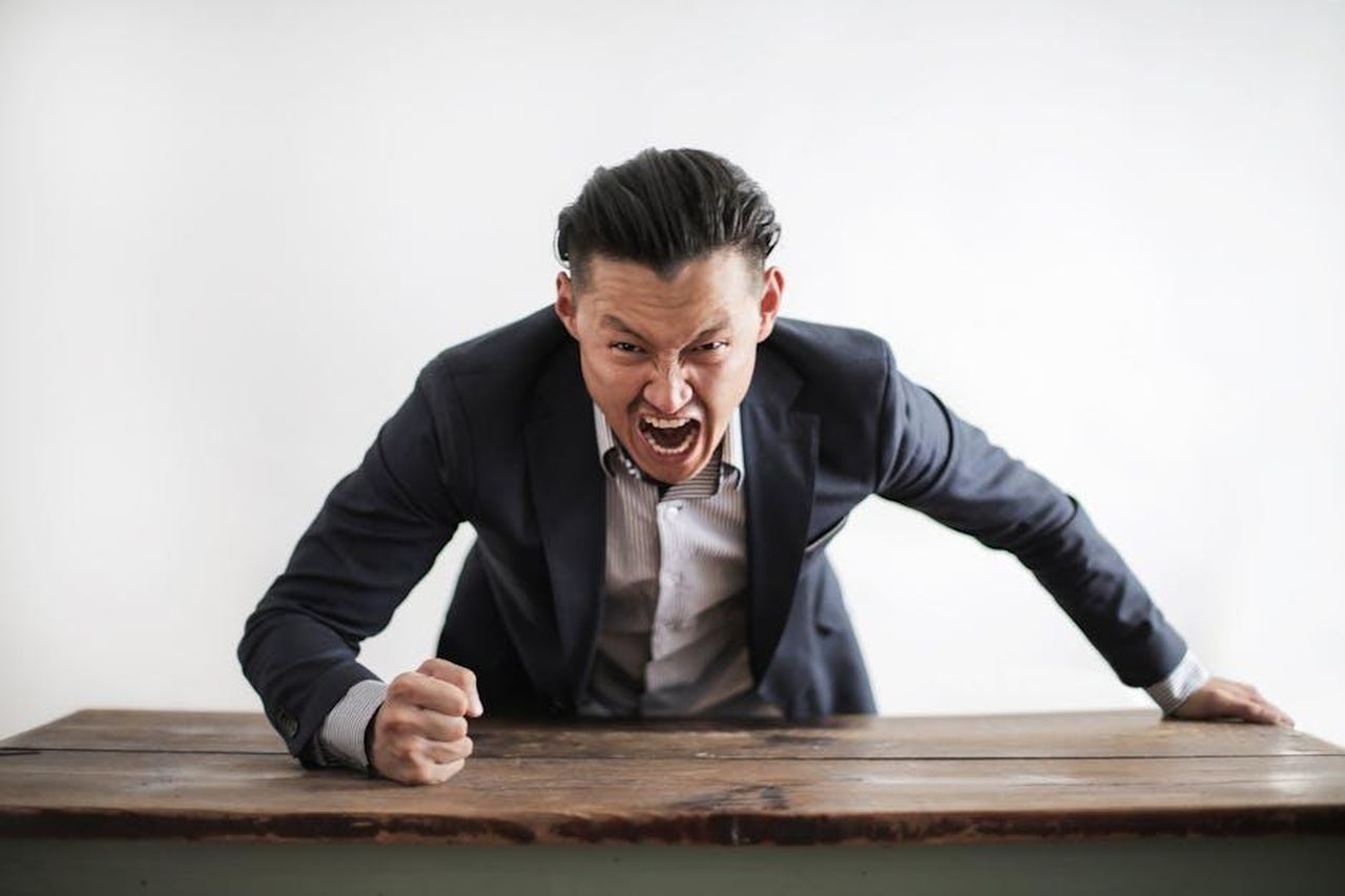 Le_tensioni_tra_Giglio_e_Stefania_U6uJgQjTEp - Confidenze24 Source: Andrea Piacquadio - pexels - Expressive angry businessman in formal suit looking at camera and screaming with madness while hitting desk with fist