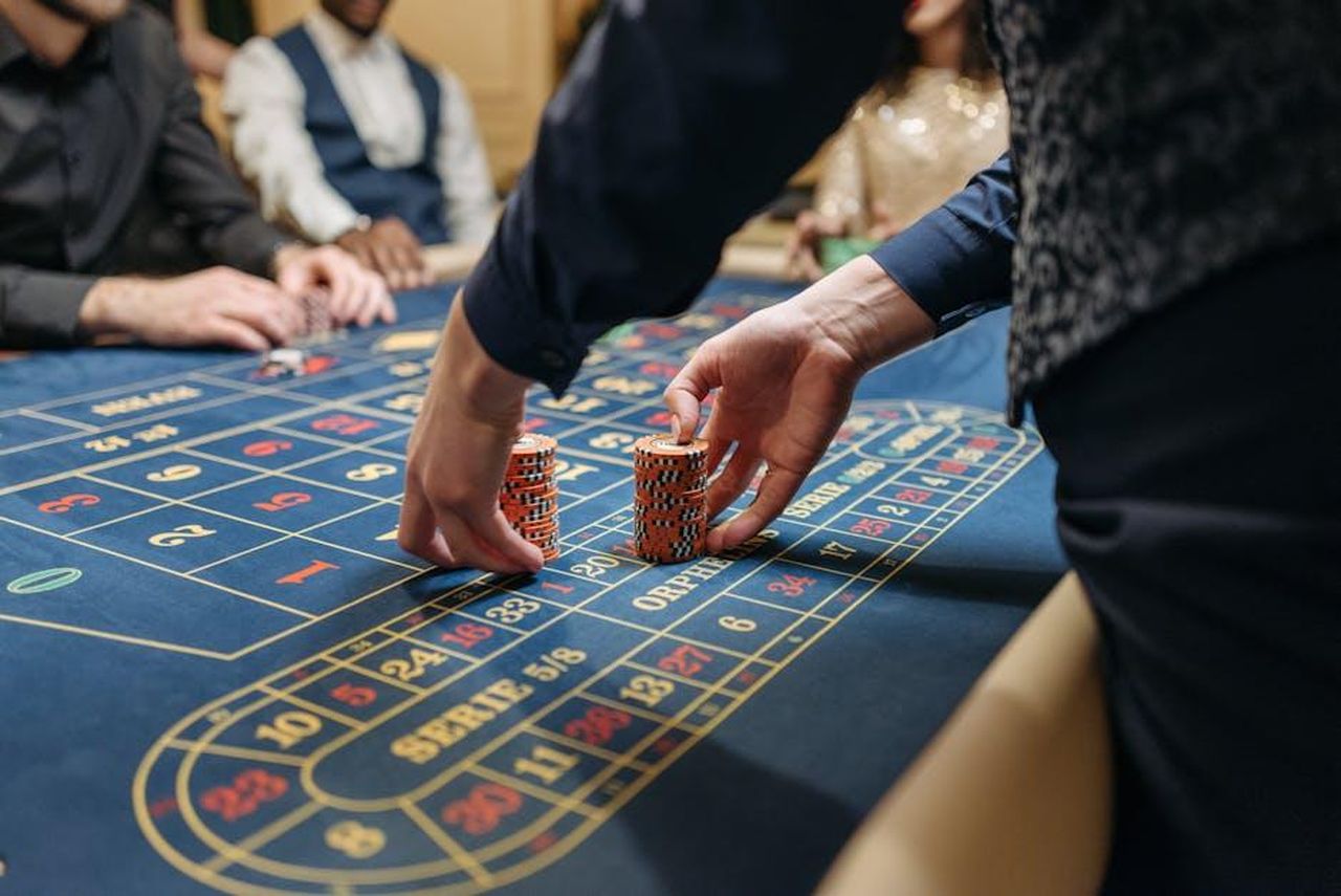 Leliminazione_di_Antonio_da_Amici_24_94YJk3LbtH - Confidenze24 Source: Pavel Danilyuk - pexels - Close-up of players placing poker chips on a blue roulette table in a casino setting.