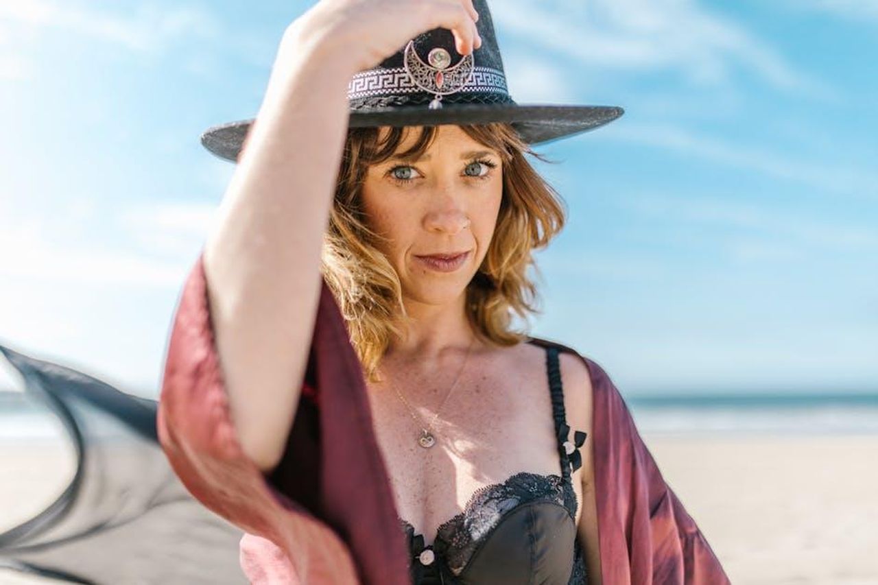 Leone_dominare_la_scena_KKutX1JpoM - Confidenze24 Source: RDNE Stock project - pexels - A captivating portrait of a woman in a witch hat on the sunny beach, evoking magical vibes.