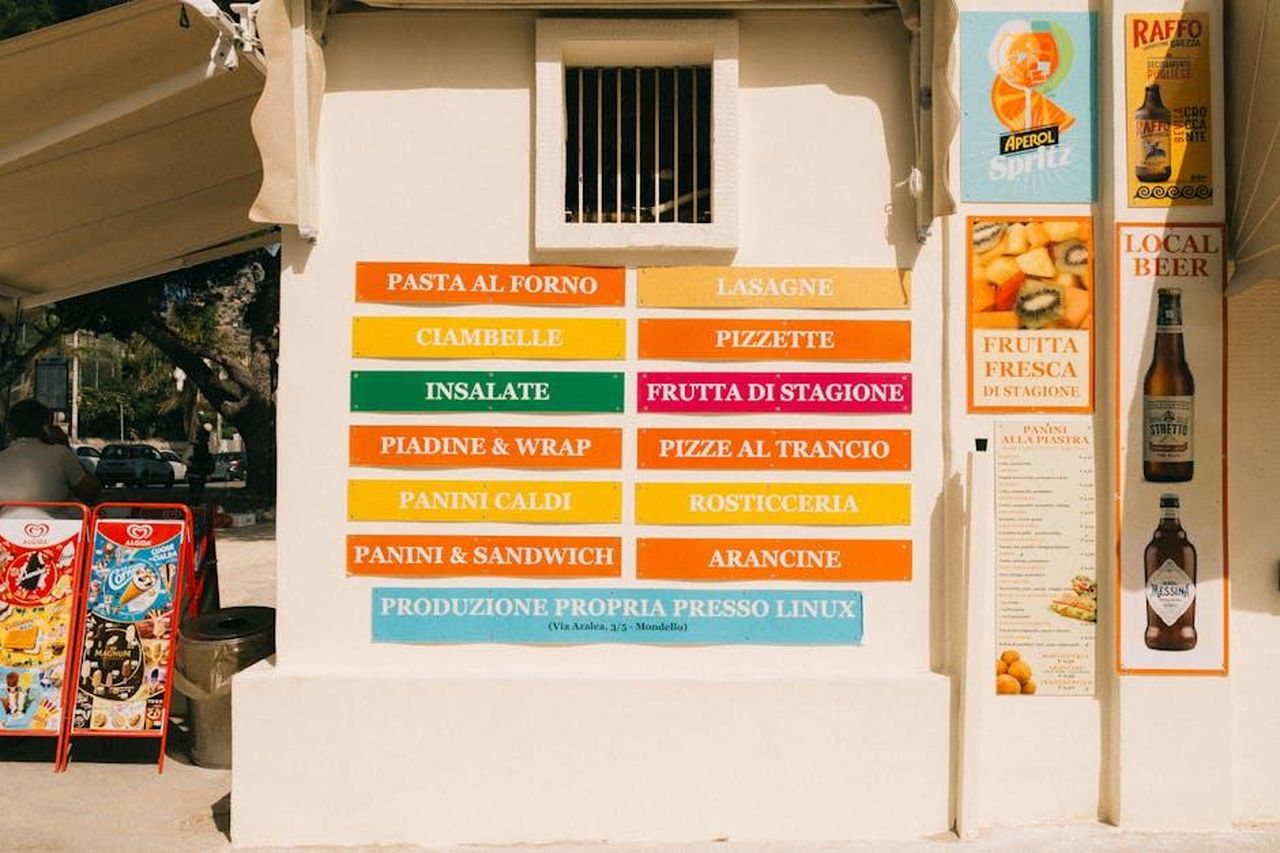 Leone_tensioni_finanziarie_4uRKmurqpF - Confidenze24 Source: Manfredi Taglialavoro - pexels - A vibrant food stand in Mondello, Palermo, Sicilia, showcasing traditional local dishes.