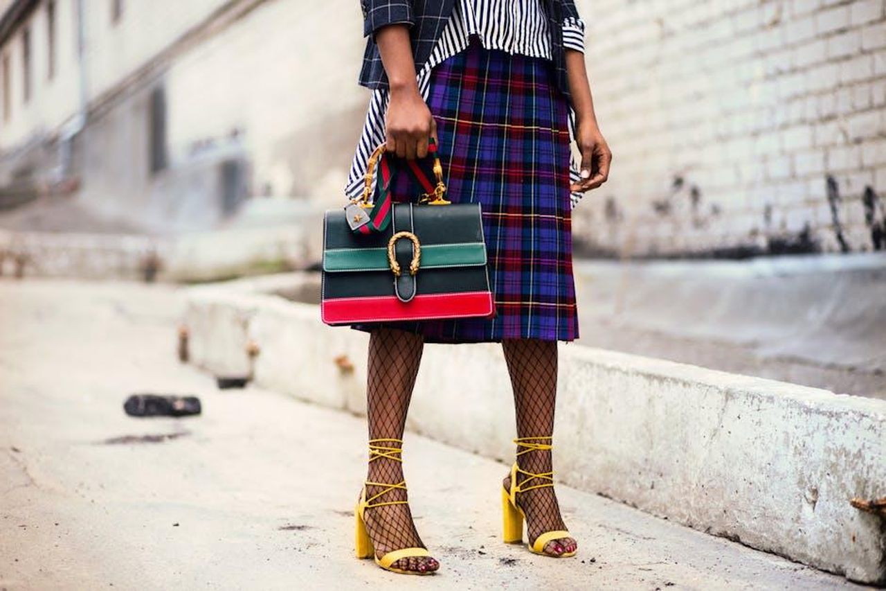 Lexi_Hughes_un_futuro_brillante_OhajpjDYO9 - Confidenze24 Source: Godisable Jacob - pexels - Fashion-forward outfit with plaid skirt and colorful handbag in urban setting.