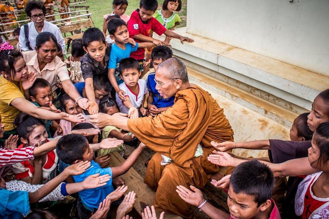 Limpegno_di_Kitty_con_Centrepoint_FzZHV34yfJ - Confidenze24 Source: Suraphat Nuea-on - pexels - A Buddhist monk sharing gifts with children, capturing a moment of compassion and cultural tradition.
