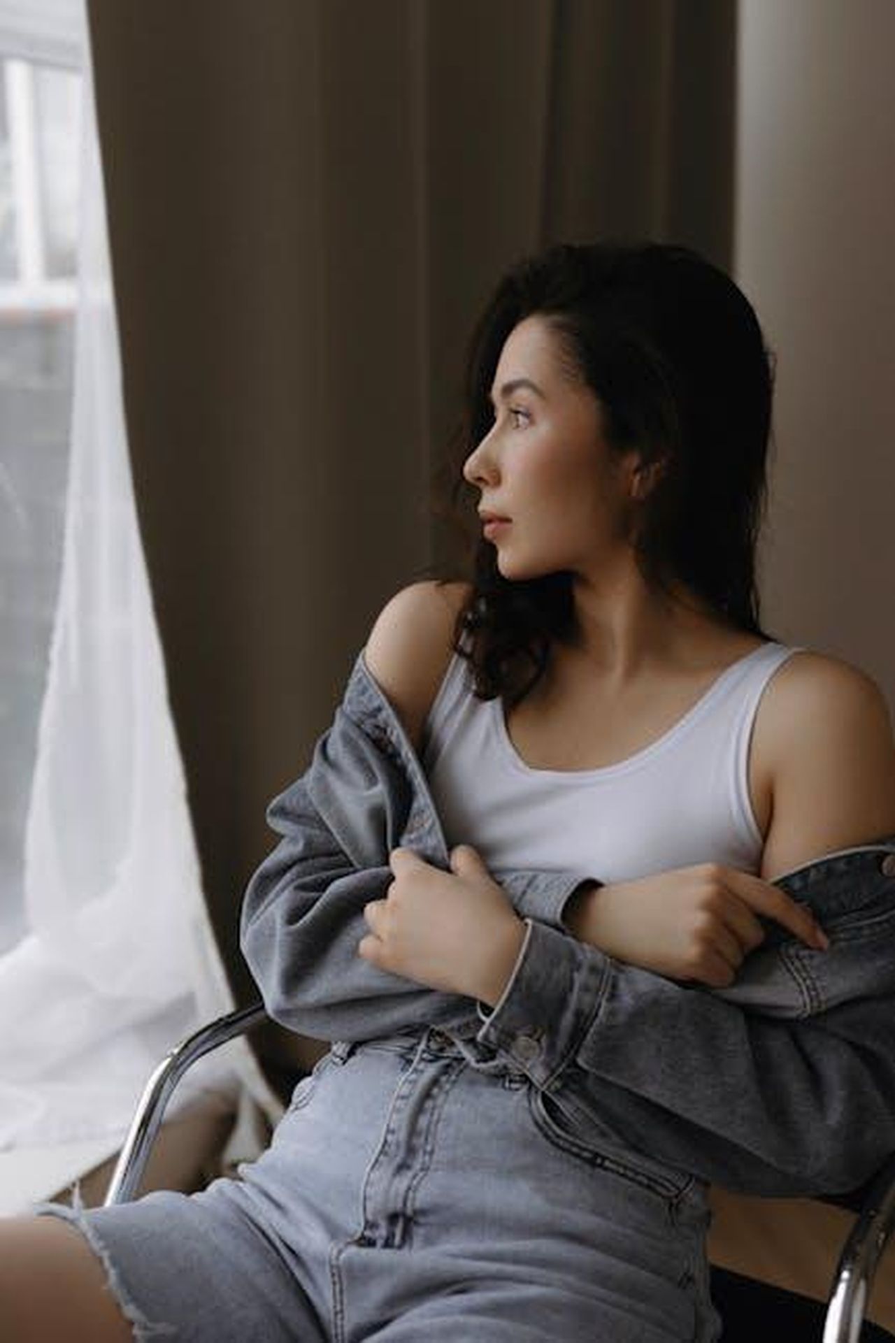 Limportanza_dellintrospezione_per_Kerry_Washington_op98nVxbjr - Confidenze24 Source: Alina Matveycheva - pexels - A thoughtful woman in a denim jacket and jeans gazes out a window.