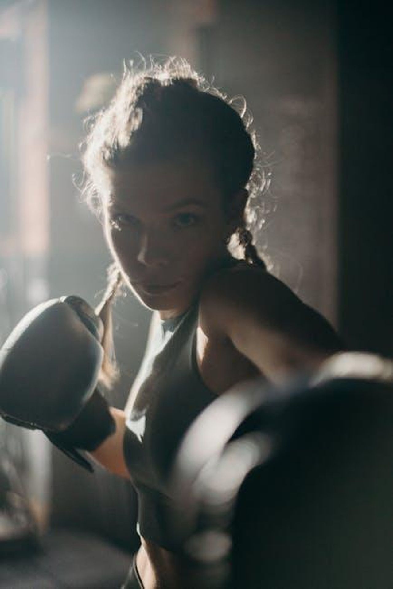 Limportanza_di_Wilson_e_Chiles_per_le_donne_nello_sport_59r3vMUdy2 - Confidenze24 Source: cottonbro studio - pexels - Focused female boxer in action, throwing a punch in a dimly lit gym.