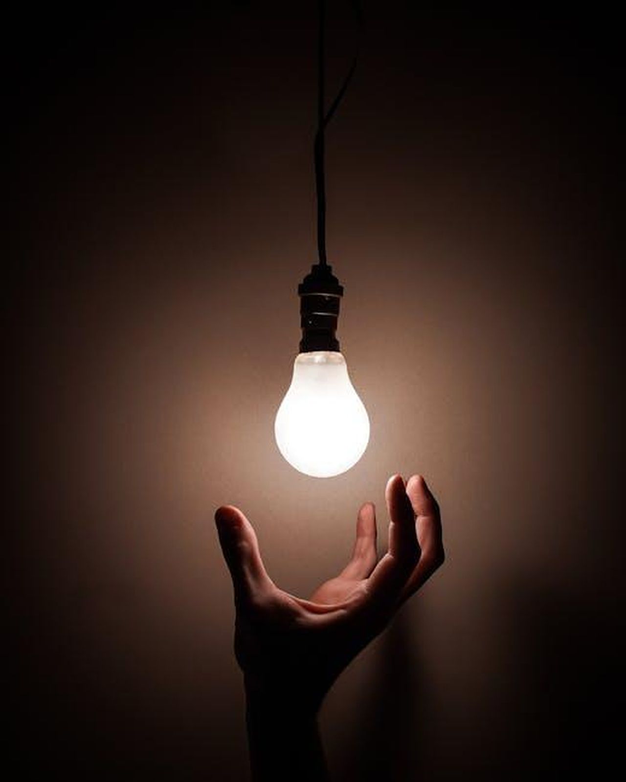 Lispirazione_di_Beyonc_per_il_Brand_I3viXCV0Eu - Confidenze24 Source: Luca Nardone - pexels - A hand reaching towards a glowing hanging light bulb symbolizing creativity and illumination.