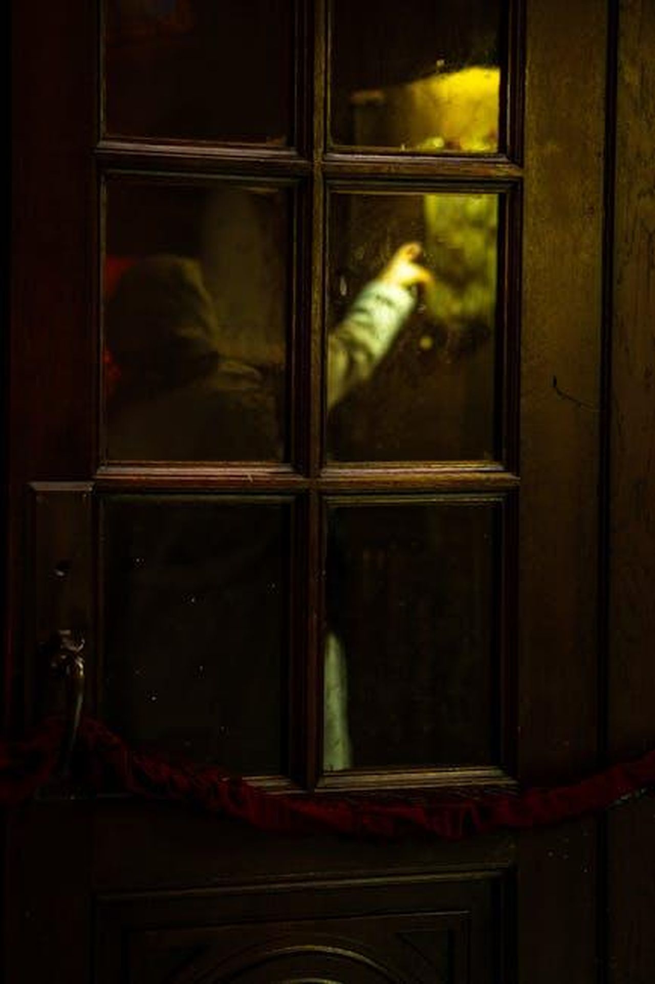 Lope_e_Salvador_un_segreto_da_nascondere_uyW3eSBmbo - Confidenze24 Source: Gökhan Çınar - pexels - A shadowy figure reaches towards a light behind an old wooden glass door, creating intrigue and mystery.