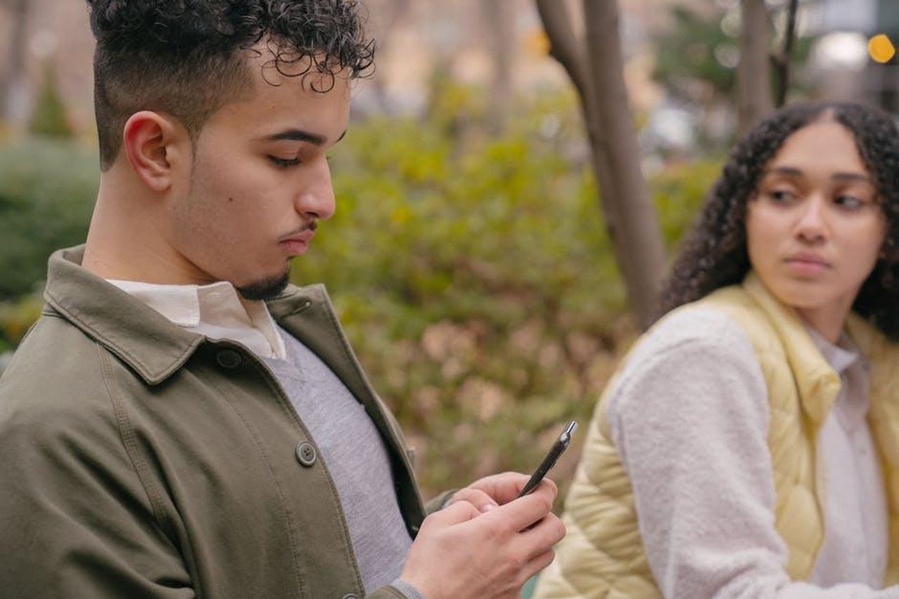 Manuel_geloso_di_Pino_Rosa_stanca_la_trama_del_28_febbraio_eaFK5XfbFJ - Confidenze24 Source: Budgeron Bach - pexels - A young couple sitting outdoors with a smartphone, capturing casual moments and emotions.