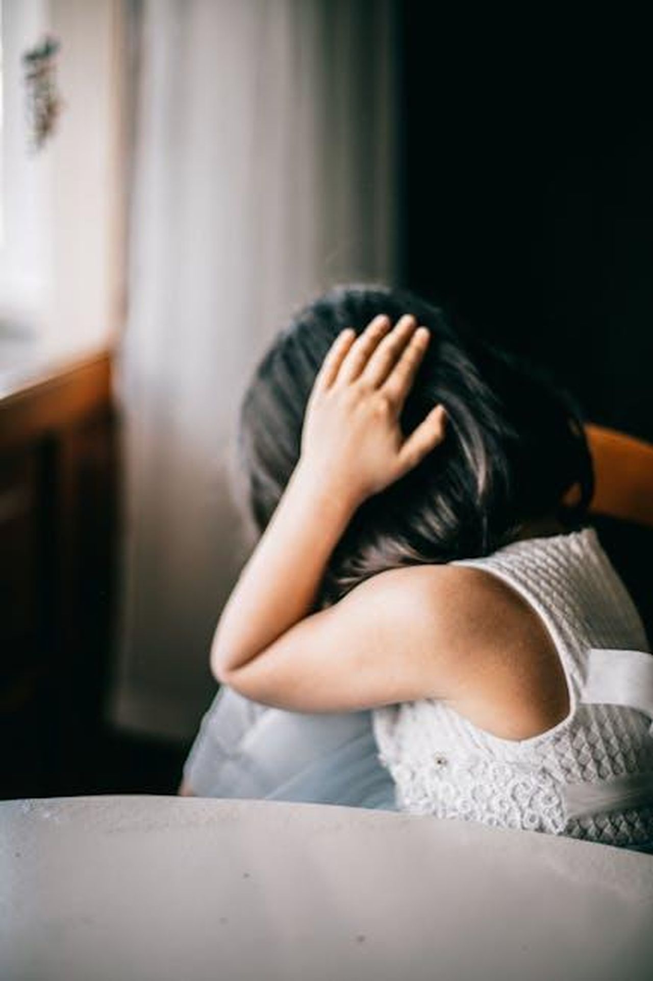 Marcello_affranto_Mimmo_sofferente_MStof82sXM - Confidenze24 Source: Meruyert Gonullu - pexels - Young girl in emotional distress, sitting indoors with hand on head.