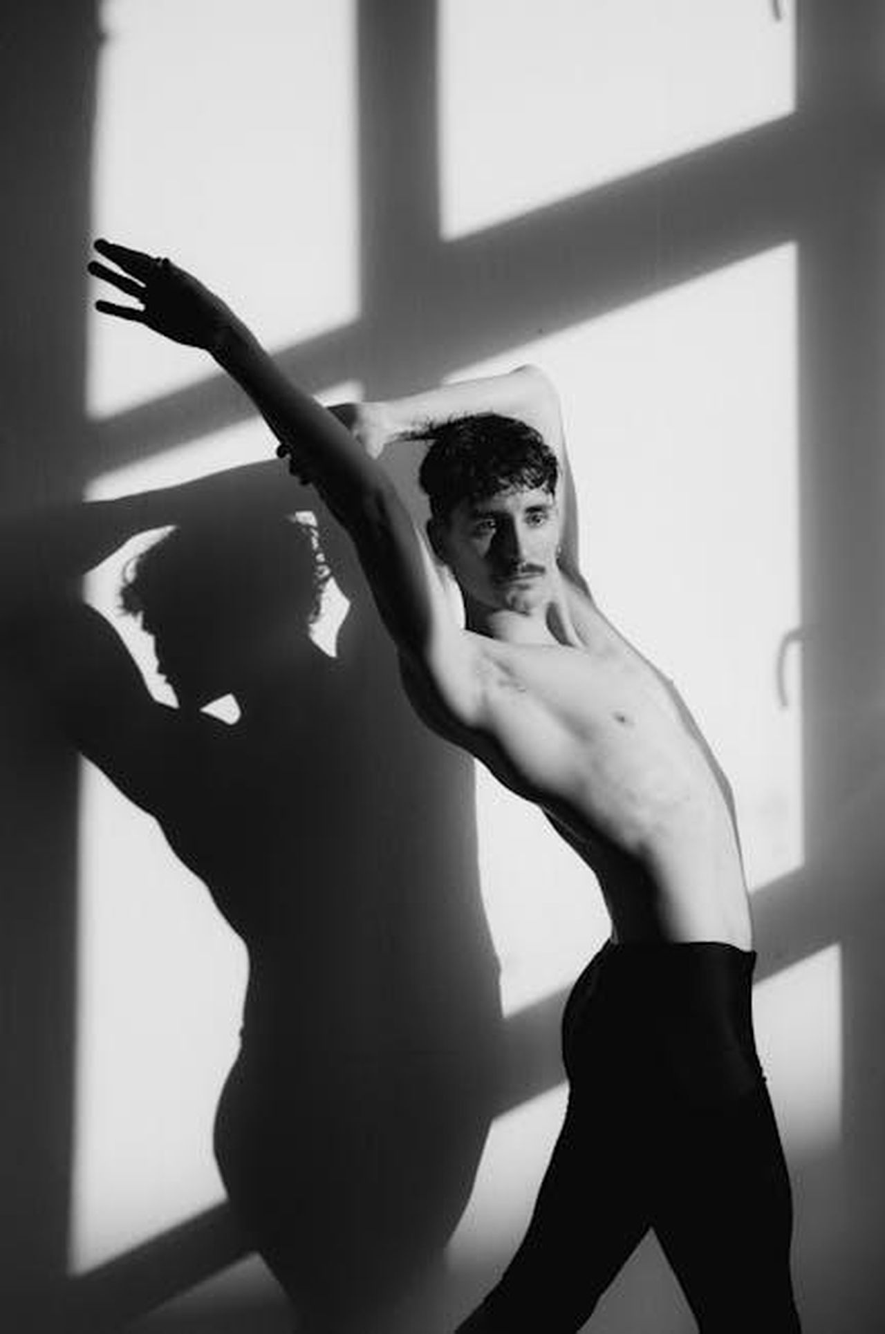 Mario_incastrato_da_una_segnalazione_anticipazioni_Uomini_e_donne_gUlG1ZB7M9 - Confidenze24 Source: Cathy B. - pexels - Artistic black and white photo of a male dancer striking a pose against a shadowed wall.