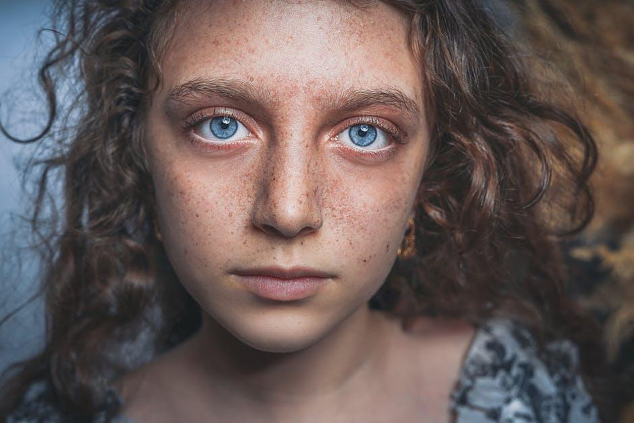 Marta_scossa_dal_ritorno_di_Vittorio_ipotesi_Il_Paradiso_delle_signore_ultime_puntate_mh25vYkmXI - Confidenze24 Source: shahin khalaji - pexels - Close-up portrait of a freckled young girl with striking blue eyes and curly hair, evoking a sense of mystery.