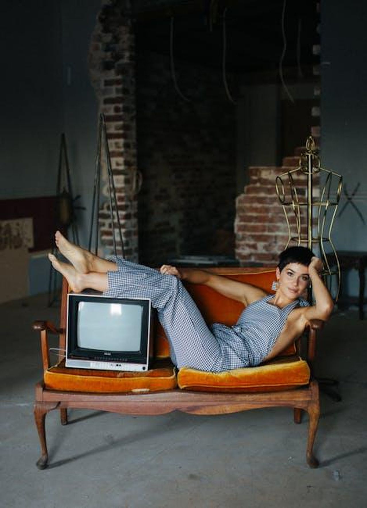 Melanie_in_una_zona_di_guerra_2Gk1K5wx9f - Confidenze24 Source: Rachel Claire - pexels - Stylish woman posing on vintage sofa with an old TV in a rustic setting.