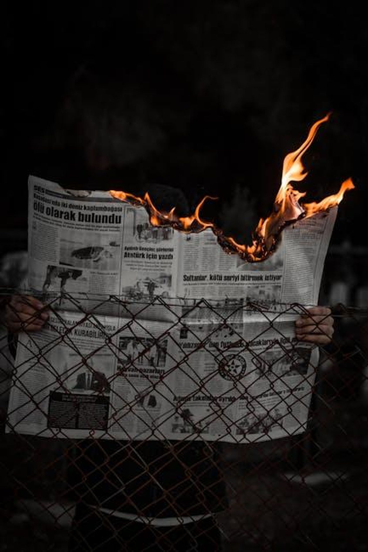Michelle_Keegan_e_Mark_Wright_ricevono_un_avvertimento_sinistro_prima_dellintrusione_mJQM5LQhq6 - Confidenze24 Source: beytlik - pexels - Dramatic image of hands holding a burning newspaper against a dark backdrop, with flames illuminating the scene.