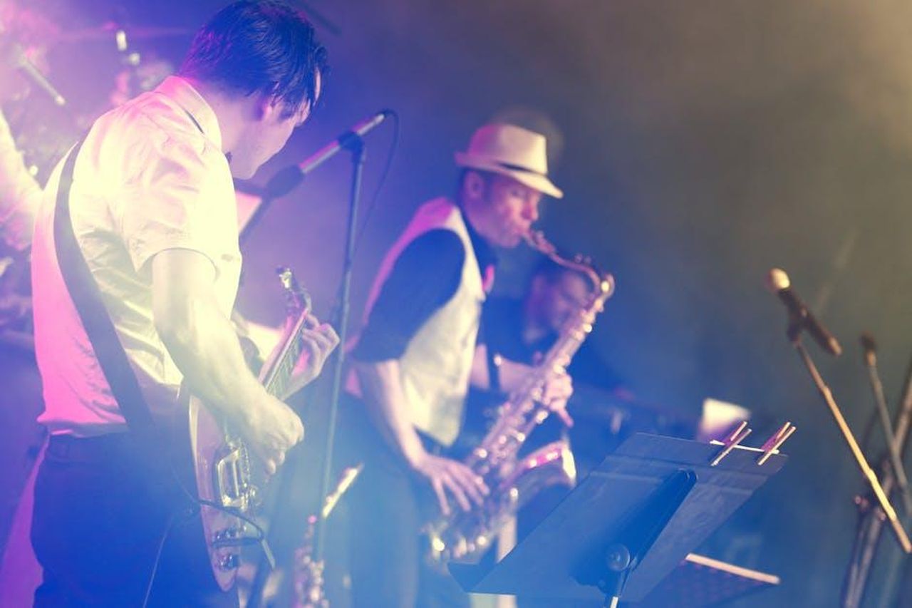 Musica_live_con_la_band_di_Nicola_Ballo_Balestri_UQ895ihoiS - Confidenze24 Source: Tuur Tisseghem - pexels - Vibrant stage performance featuring a guitarist and saxophonist at an energetic live concert.