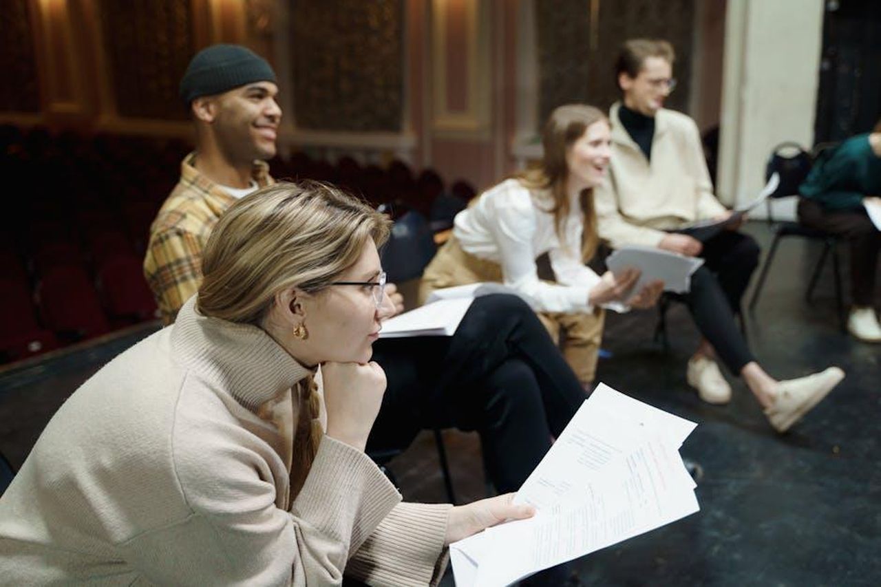 Nelle_ultime_puntate_de_La_Promessa_8LR7UAB1W0 - Confidenze24 Source: cottonbro studio - pexels - Actors rehearsing a play on stage, holding scripts and discussing roles in a theater setting.