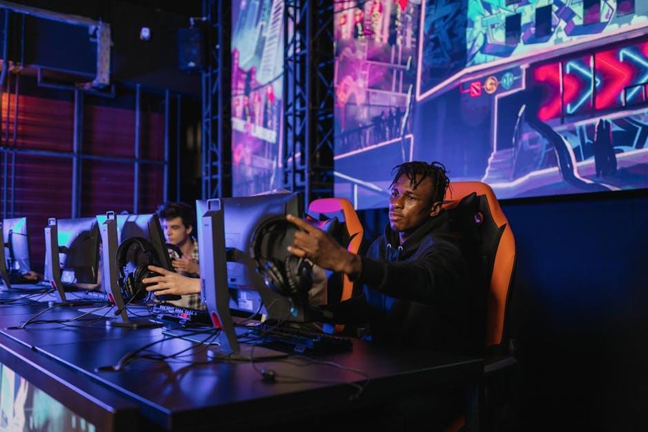 Nomination_al_Grande_Fratello_cosa_dicono_i_sondaggi_TXpag1Y6i0 - Confidenze24 Source: Alena Darmel - pexels - Two gamers intensely focused in a professional eSports competition with vibrant game visuals.