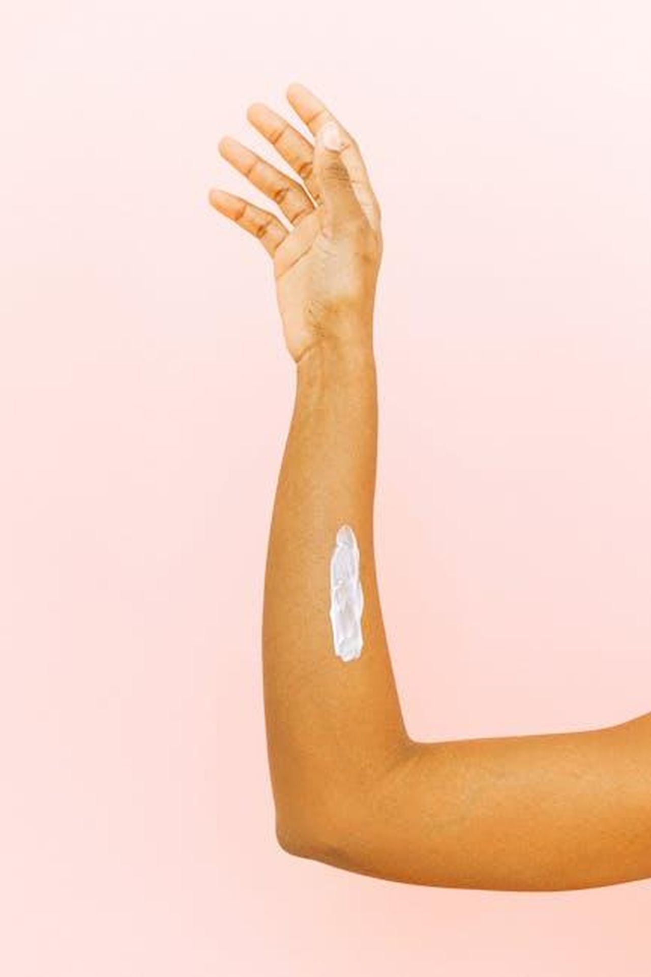 Non_mi_sento_una_guerriera_u10yDswupm - Confidenze24 Source: Anna Shvets - pexels - A close-up of a skincare routine with lotion on an arm, set against a pink backdrop.