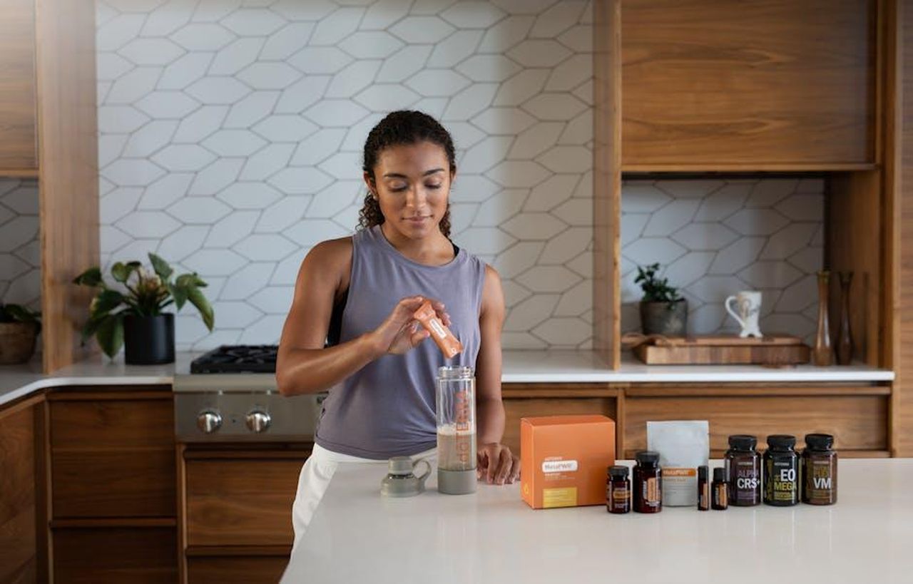 Oli_essenziali_per_la_stagione_delle_eclissi_JlscdjrMCA - Confidenze24 Source: doTERRA International, LLC - pexels - A woman uses essential oils and supplements in a contemporary kitchen for wellness.