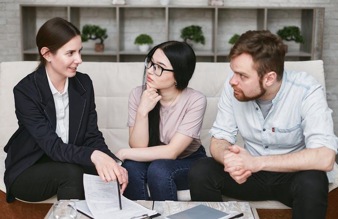 Opinioni_degli_utenti_pZ3wPcPvp9 - Confidenze24 Source: Mikhail Nilov - pexels - Three adults discussing business inside, focused on cooperation and strategy.