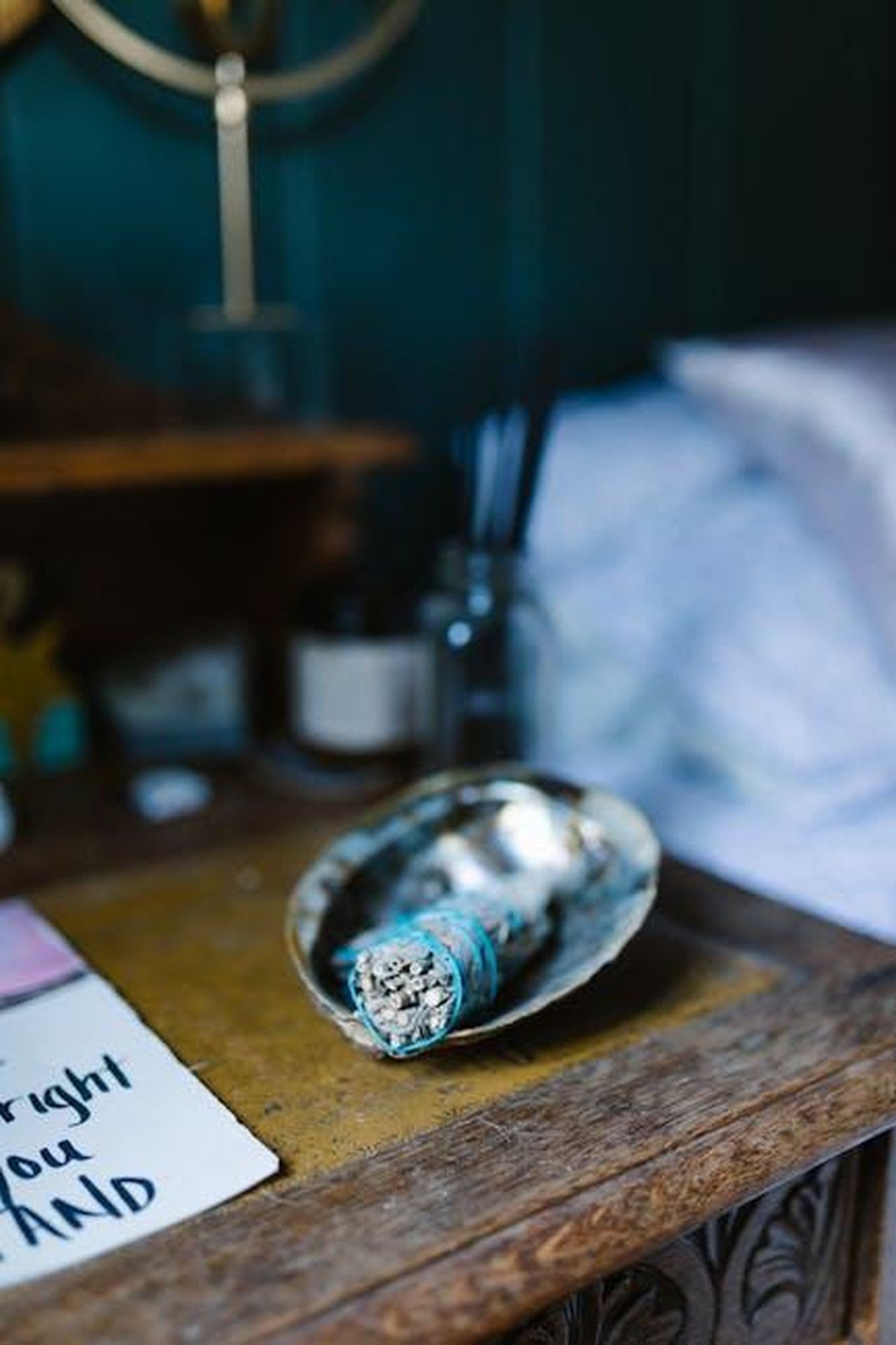 Oroscopo_degli_ultimi_quattro_segni_6okCqo0w4B - Confidenze24 Source: RDNE Stock project - pexels - A rustic wooden table with a smudge stick in a shell, candles, and relaxing decor for a serene atmosphere.
