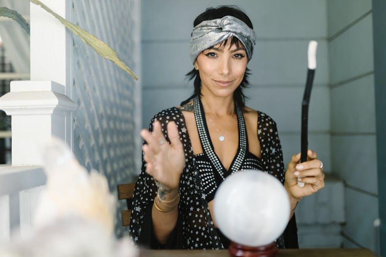 Oroscopo_degli_ultimi_quattro_segni_kCqw1Z51Bj - Confidenze24 Source: RDNE Stock project - pexels - A woman in a headband performs a mystical ritual with a crystal ball and wand.