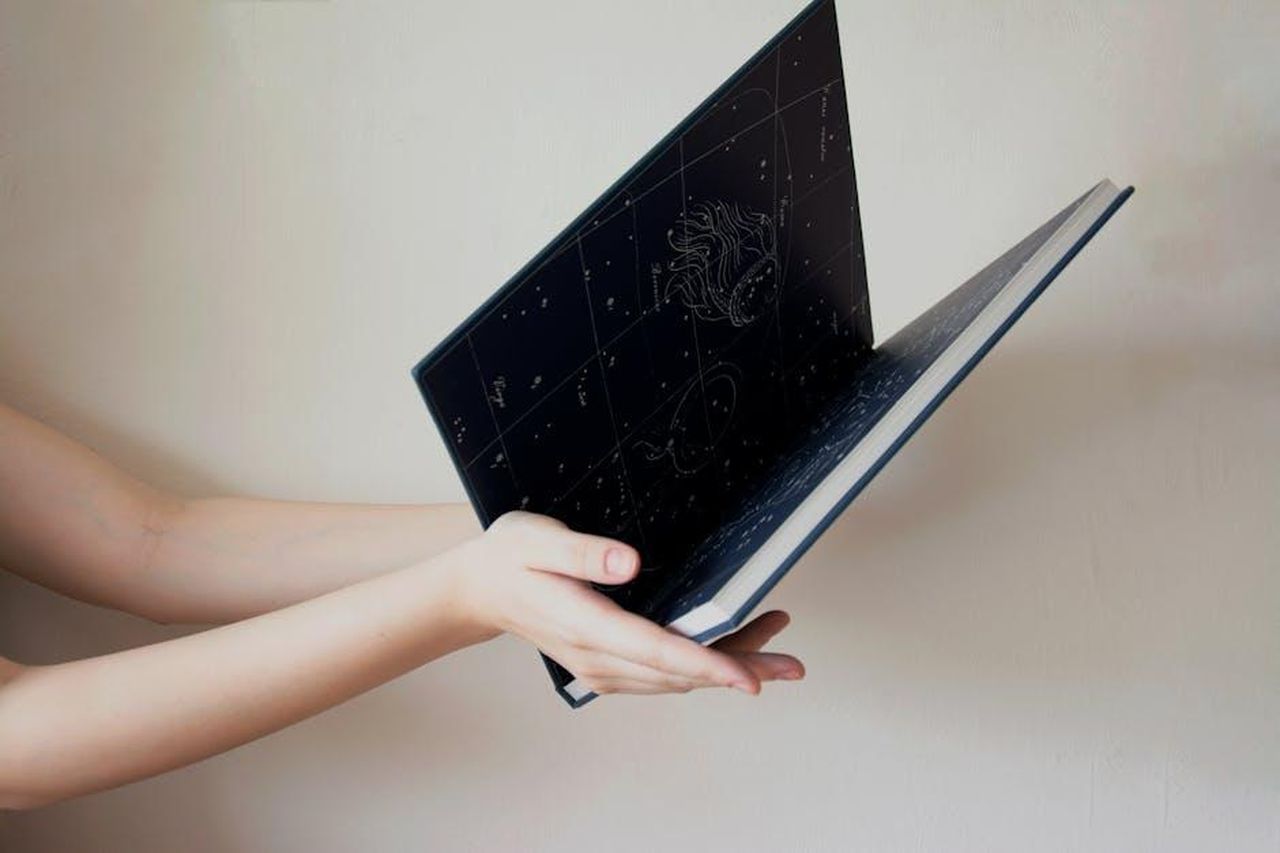 Oroscopo_di_venerd_21_febbraio_pagelle_da_Ariete_a_Cancro_0aYV3NGLkF - Confidenze24 Source: Alexa Kei - pexels - Hands holding an open book with a starry illustration, indoors.