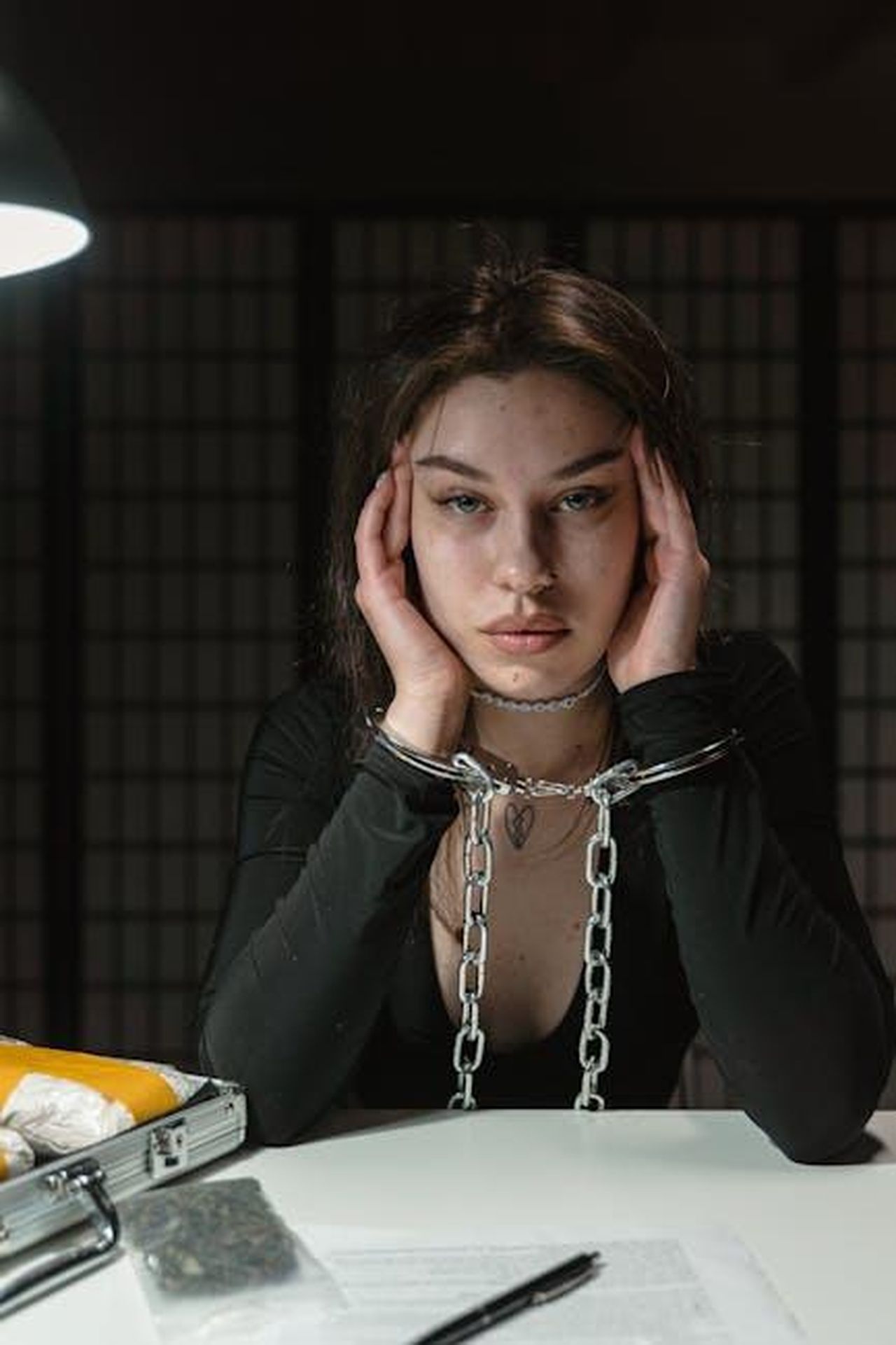 Ozan_finisce_in_carcere_dopo_laggressione_a_Refik_0mhuqwUMSW - Confidenze24 Source: MART PRODUCTION - pexels - Woman in handcuffs, sitting in a dimly-lit room, appearing contemplative.