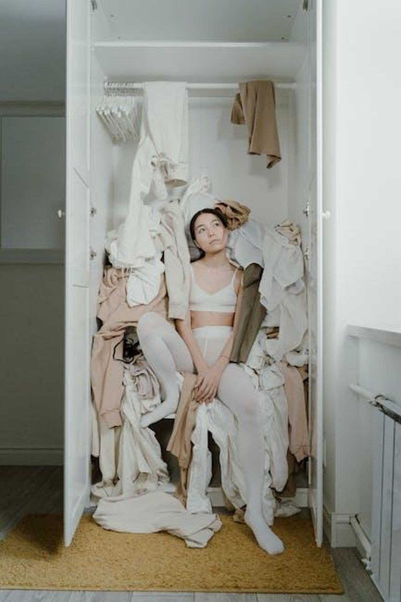 Parola_dordine_sostenibilit_K3n47hDuH1 - Confidenze24 Source: Ron Lach - pexels - A contemplative woman sits surrounded by clothes in a messy wardrobe, evoking themes of consumerism and clutter.