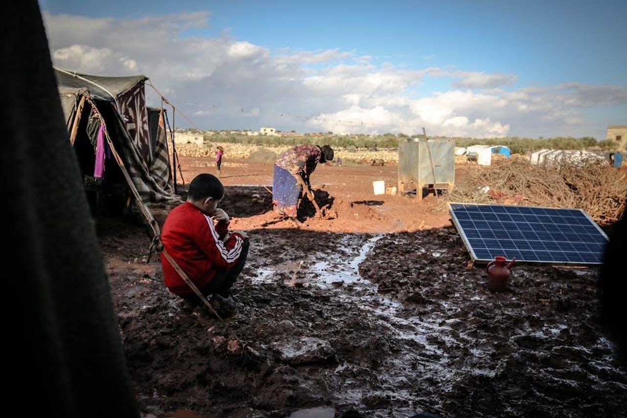 Passato_Legale_di_Simon_Guobadia_con_lImmigrazione_wlqawascXW - Confidenze24 Source: Ahmed akacha - pexels - A boy and woman in a muddy refugee camp in Idlib, Syria with tents and solar panel.