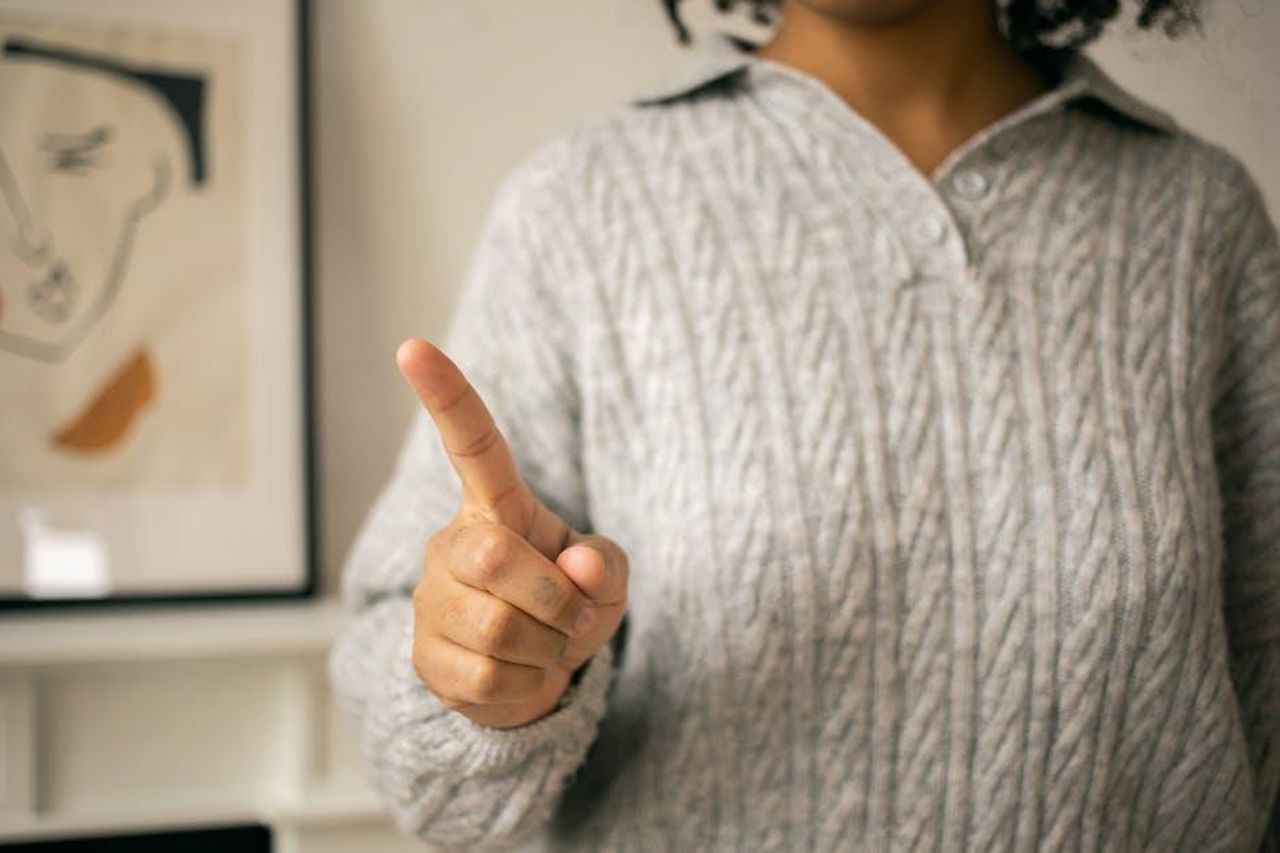Perch_dovrei_dare_un_altro_colpo_di_grazia_ad_Alfonso_0pcS87dAZg - Confidenze24 Source: Monstera Production - pexels - A close-up of a woman in a sweater gesturing 'no' indoors, capturing emotion.