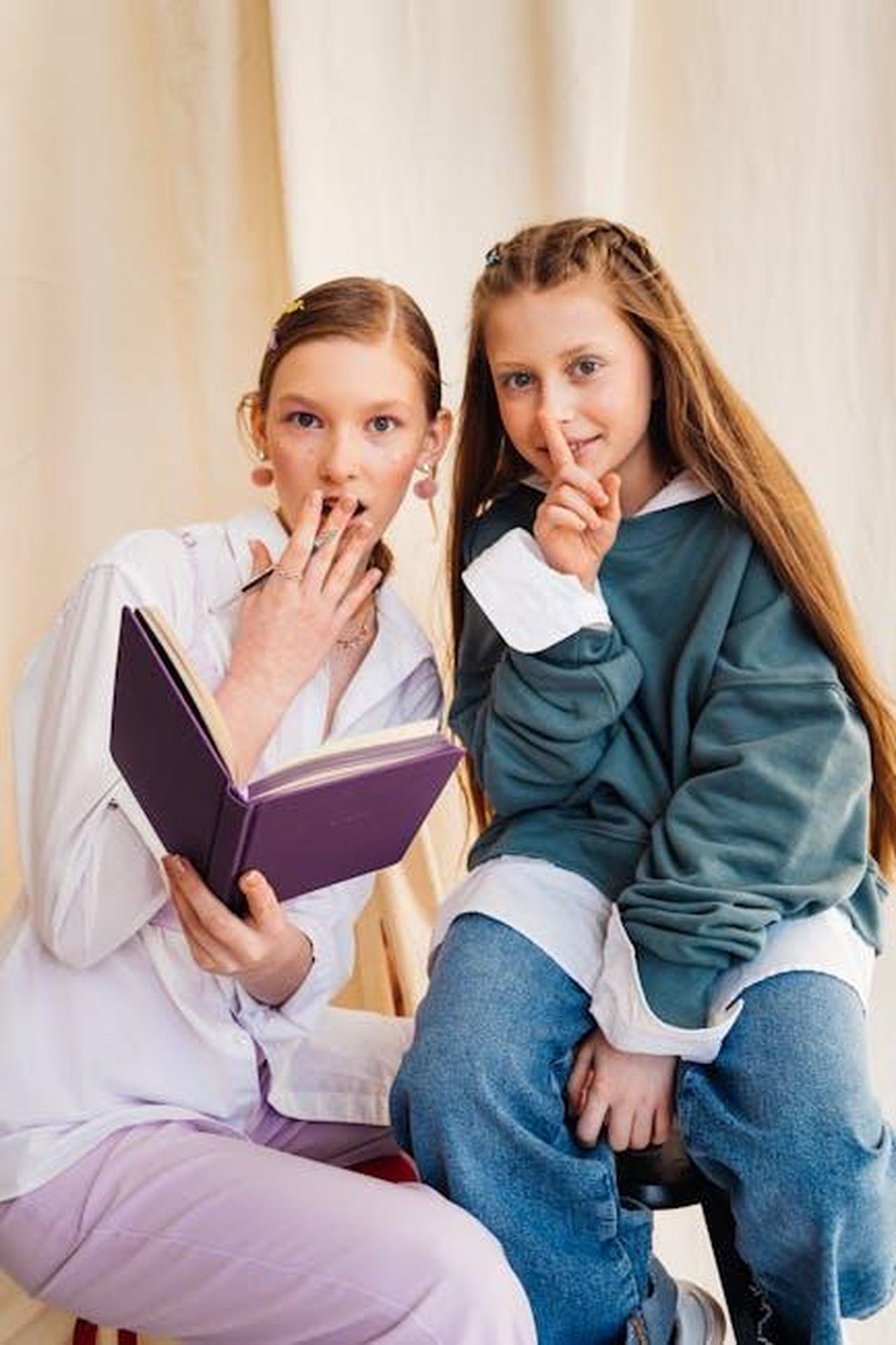 Perch_il_palazzo_non_ha_pubblicato_il_dossier_IumEJgPpsS - Confidenze24 Source: Antoni Shkraba - pexels - Two young girls sharing a book and secrets in a cozy indoor setting.