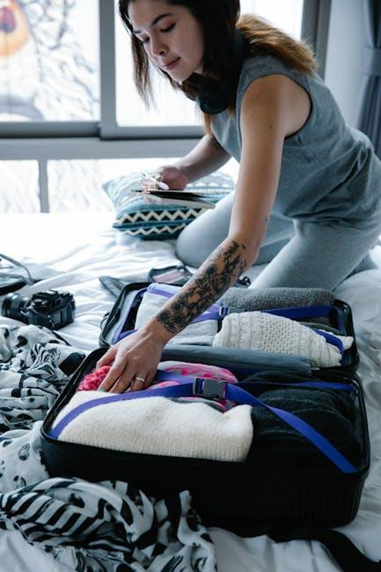 Pesci_sfera_sentimentale_solida_S4yCqwBfCE - Confidenze24 Source: Timur Weber - pexels - Woman with tattoo packs suitcase indoors during day, preparing for travel.