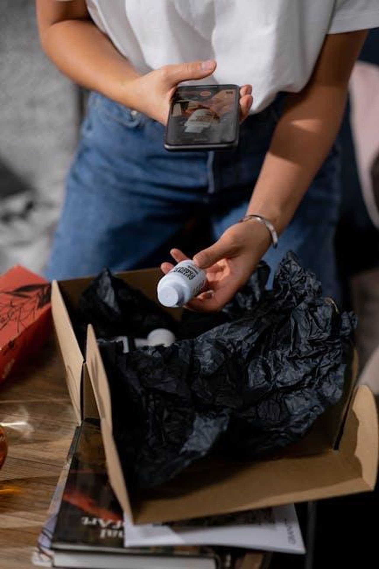 Praticit_e_comfort_del_prodotto_bYfjwibgqT - Confidenze24 Source: Ron Lach - pexels - A woman examines a bottle of cosmetics from an online order, capturing the moment on her smartphone.