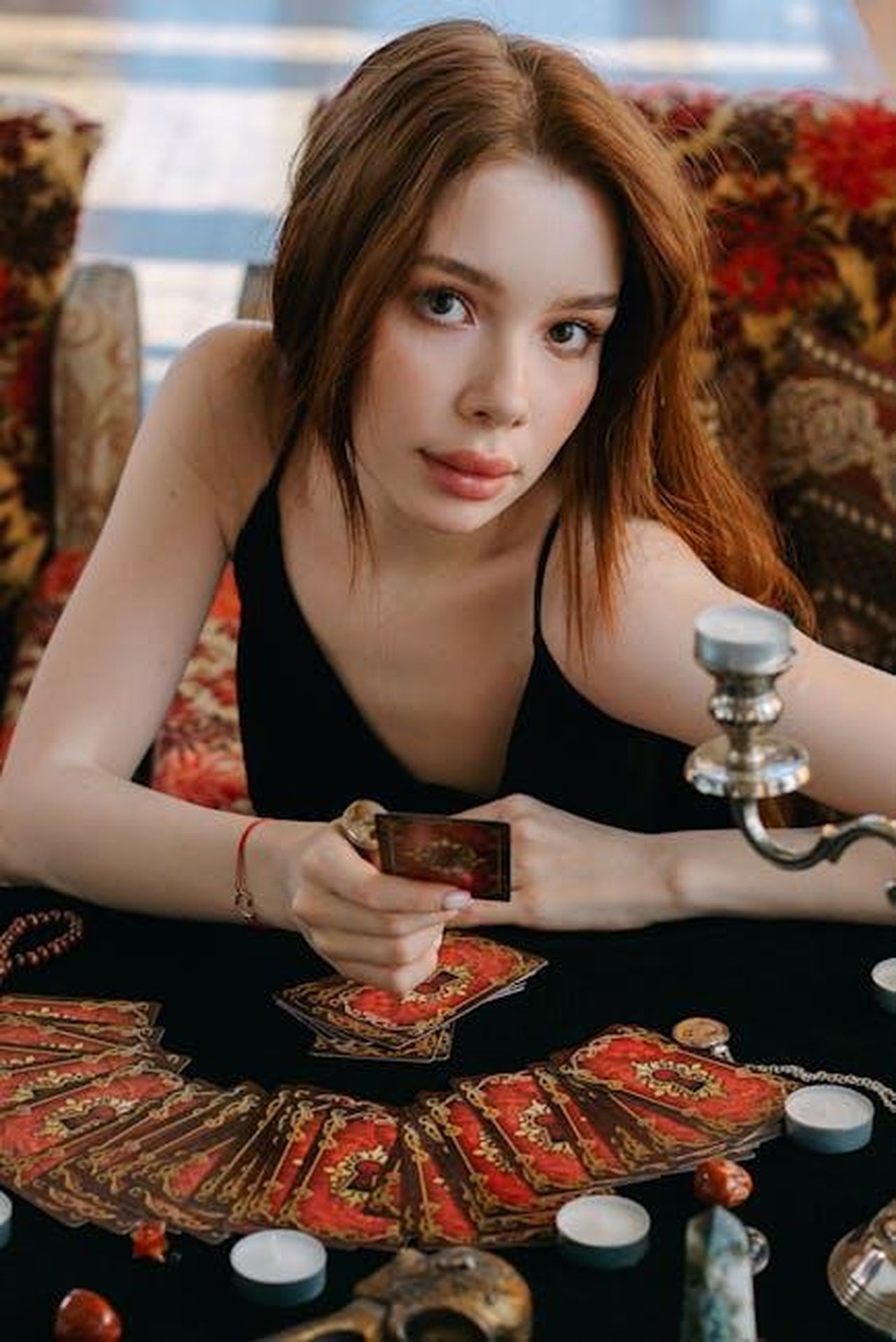 Previsioni_astrali_del_giorno_20_febbraio_pagelle_da_Leone_a_Scorpione_VbnEsxhaeU - Confidenze24 Source: Mikhail Nilov - pexels - Woman seated at a table holding a tarot card, evoking a mystical and spiritual atmosphere.