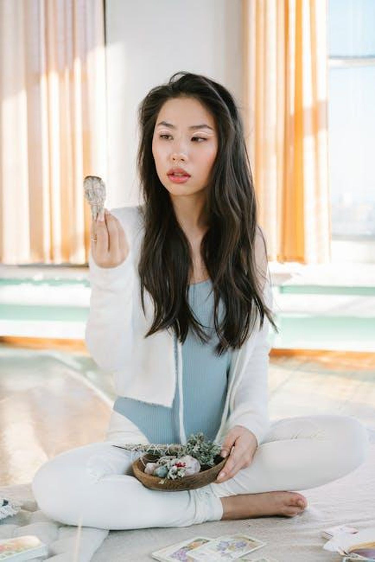 Previsioni_astrologiche_del_21_febbraio_con_posizioni_intermedie_tegISytQzu - Confidenze24 Source: Mikhail Nilov - pexels - A woman meditates indoors with sage and tarot cards in a sunlit room.