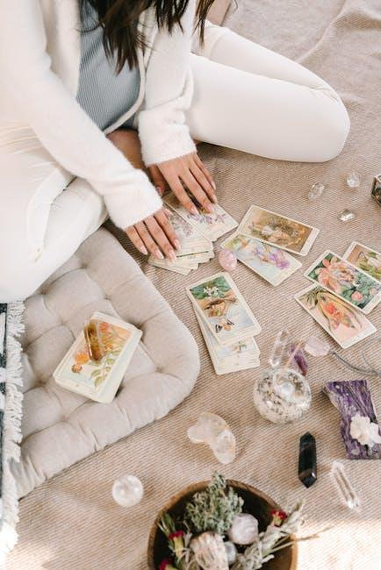Previsioni_astrologiche_marzo_2025_i_segni_flop_e_top_delloroscopo_IGeFV09sJu - Confidenze24 Source: Mikhail Nilov - pexels - A woman sits cross-legged indoors, handling tarot cards, surrounded by crystals and herbs.
