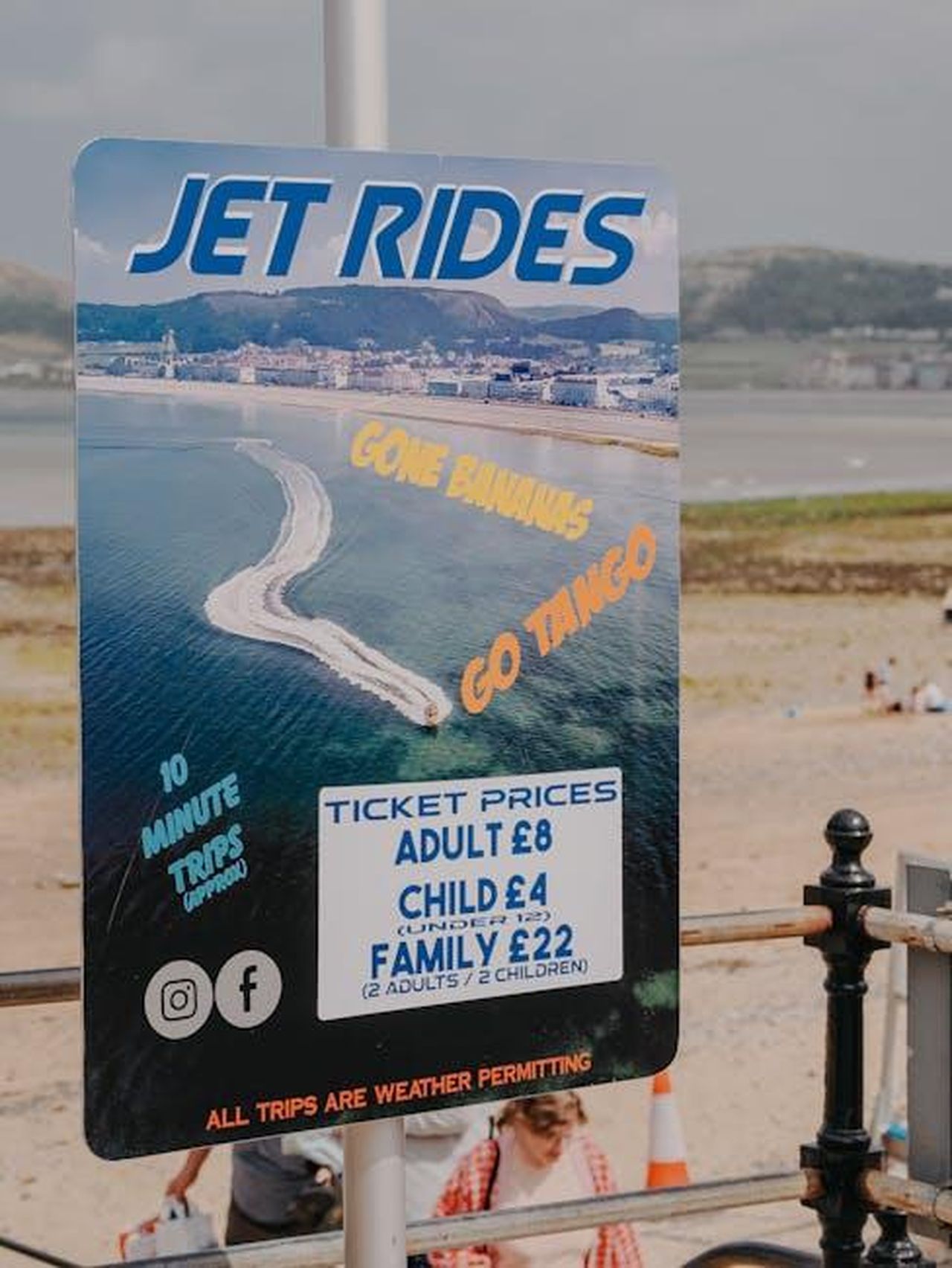 Prezzi_dei_biglietti_e_dettagli_dellevento_6hSdQCQn41 - Confidenze24 Source: Welshot Imaging - pexels - Vertical shot of a vibrant jet rides advertisement sign on a beach, highlighting fun and adventure.