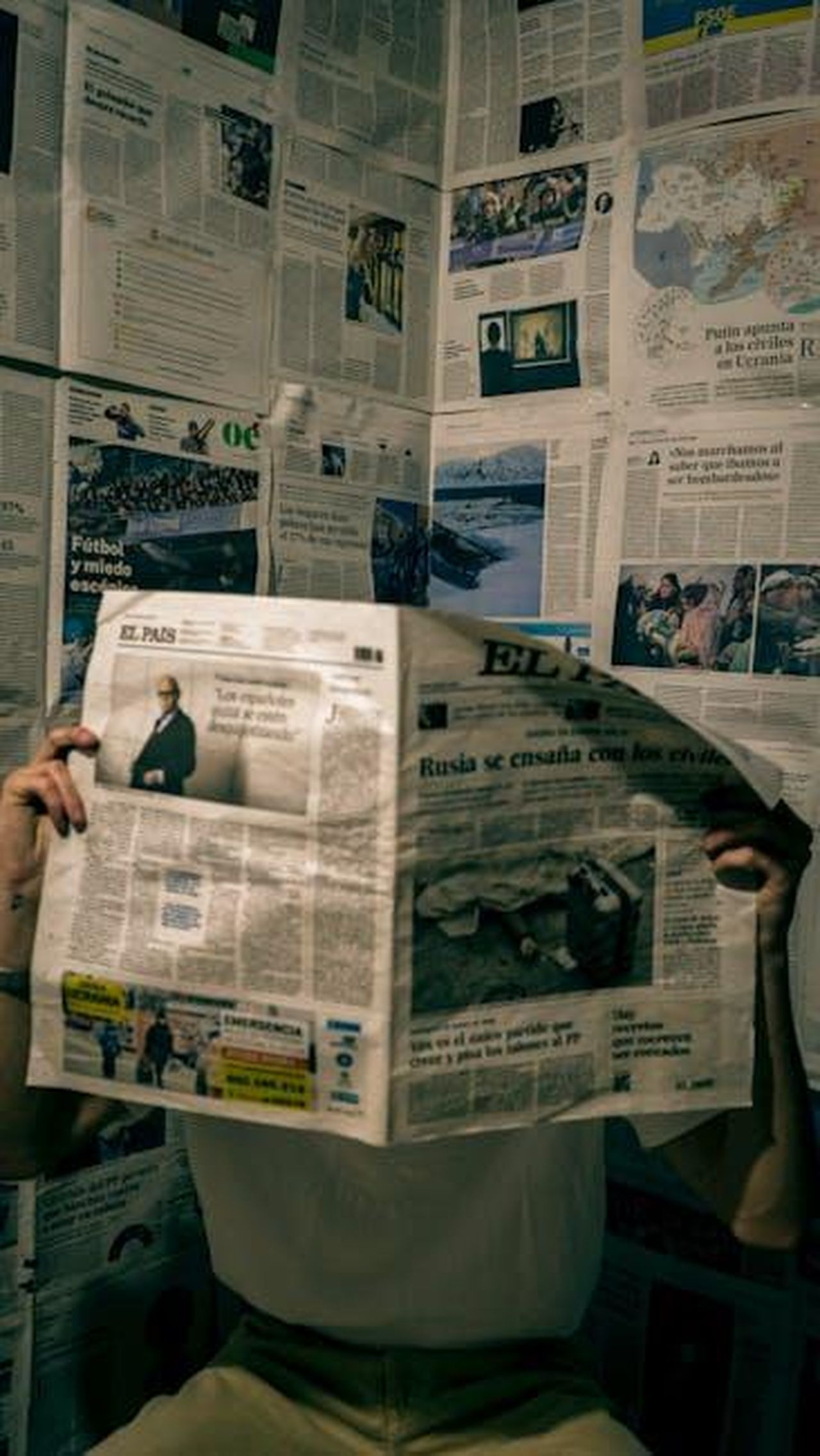 Reazioni_alla_causa_e_supporto_per_lAP_trSeu9VE0p - Confidenze24 Source: ricardo cristian - pexels - A person reads a newspaper in a room with walls covered in news articles.